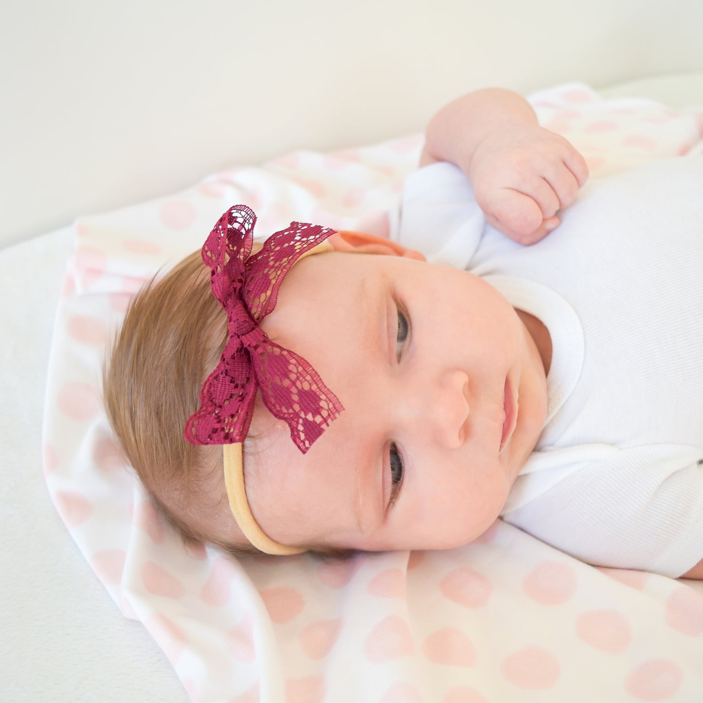 baby girl with swaddle and lace bow village baby designer gift