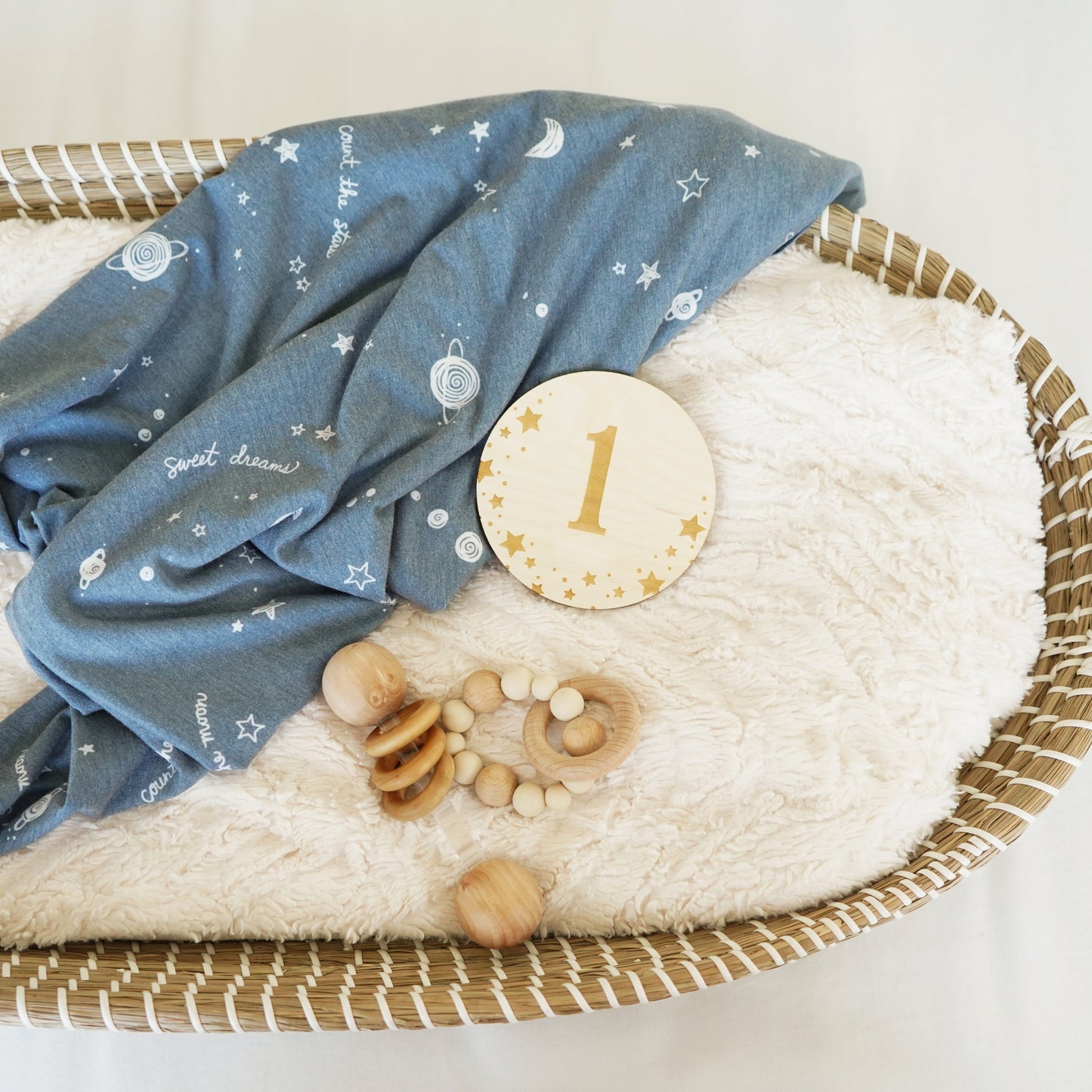 collection of blanket, basket, rattles, and monthly milestone starry dreams sign