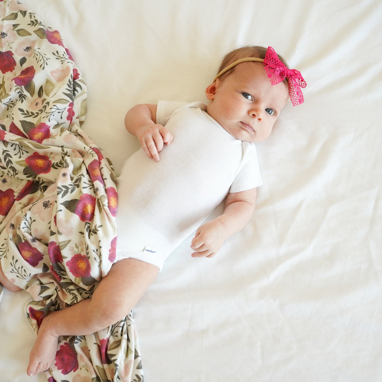 baby with fuchsia florals swaddle blanket and emma lace stretchy headband bow