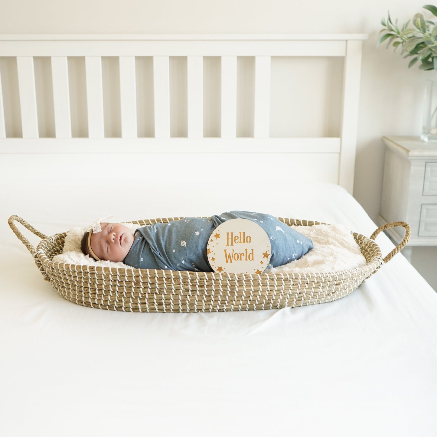 baby in bassinet with hello world star motif sign
