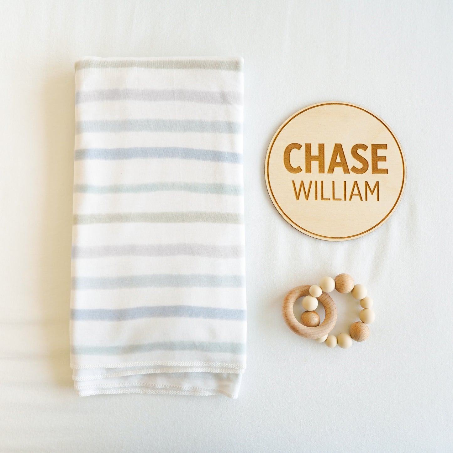 village baby stretch knit swaddle, custom name sign, and baby toy gift set