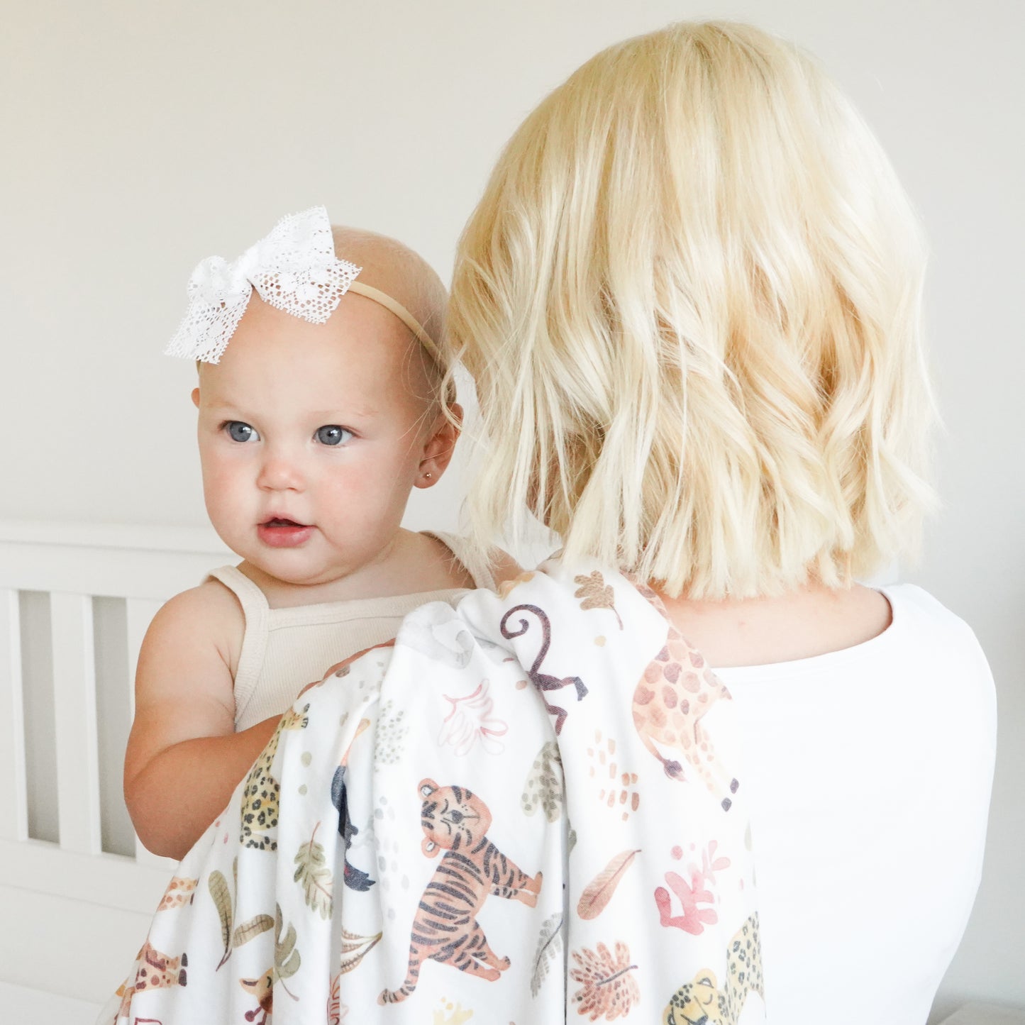 baby wearing Lily white lace bow being held y her mom with swaddle