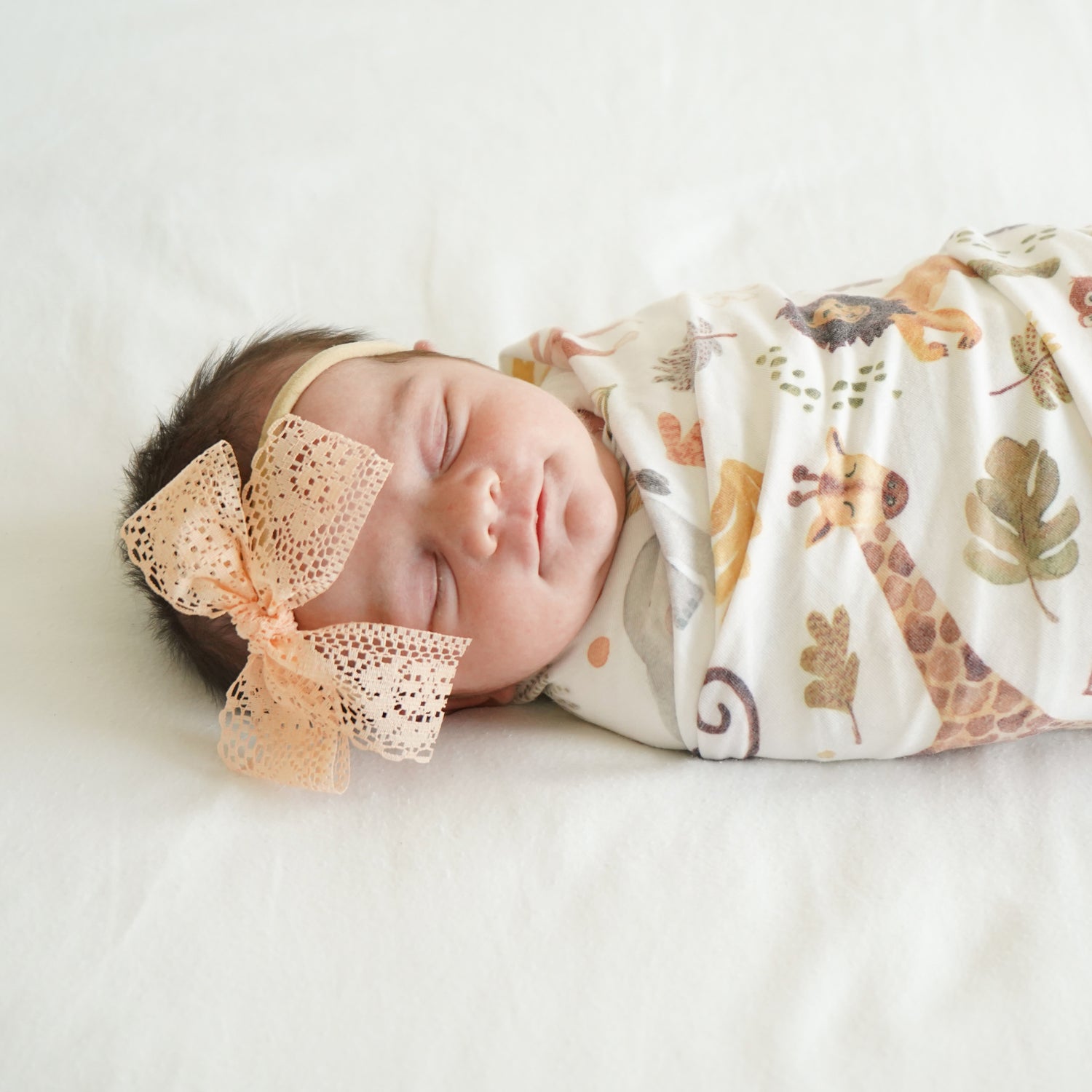 newborn peach lace harper bow on stretchy headband sleeping in safari animals swaddle