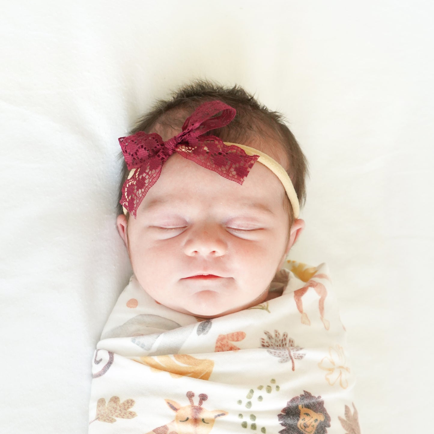swaddled baby wearing headband with lace burgundy bow 