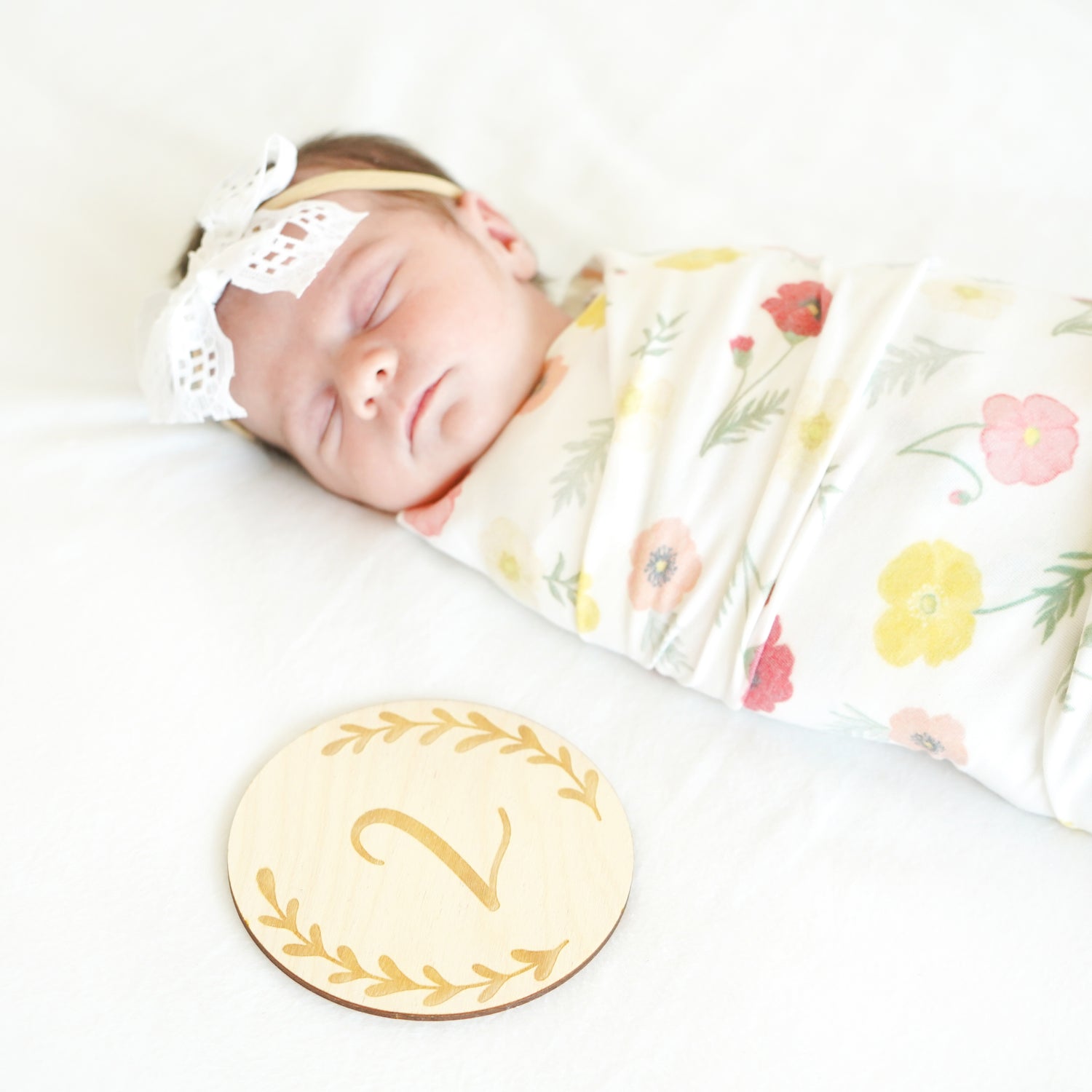 baby with 2 month age growth milestone sign disc round swaddle and bow