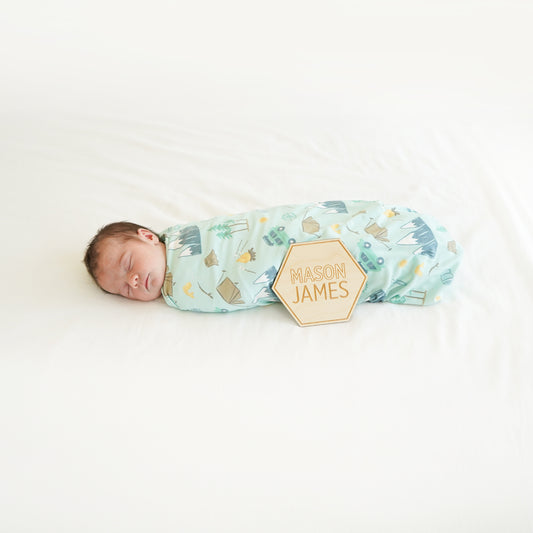 village baby boy wrapped in camping swaddle with custom wood name sign modern cute