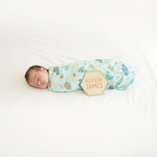 village baby boy wrapped in camping swaddle with custom wood name sign modern cute