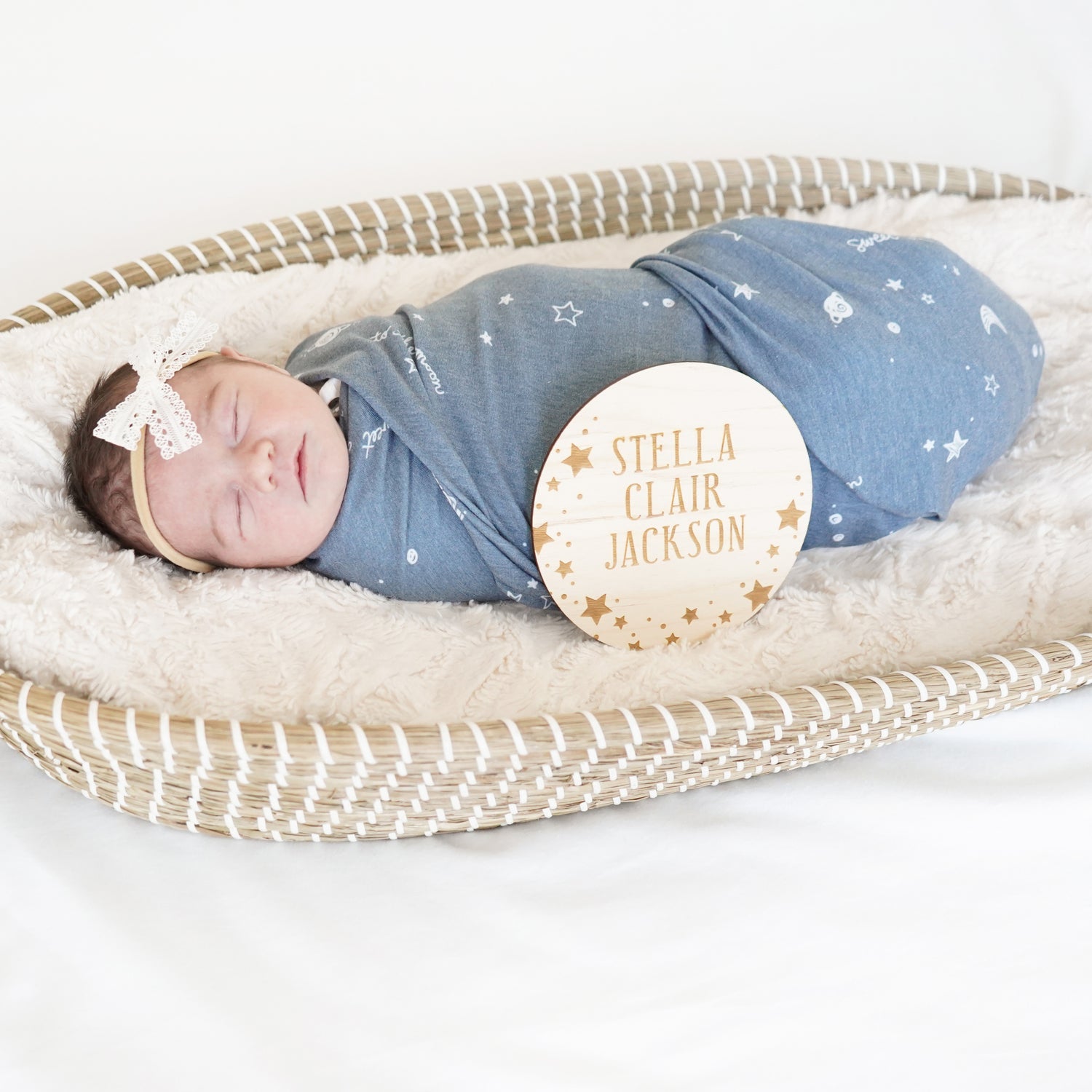 baby in basinet with swaddle, bow, and star name sign