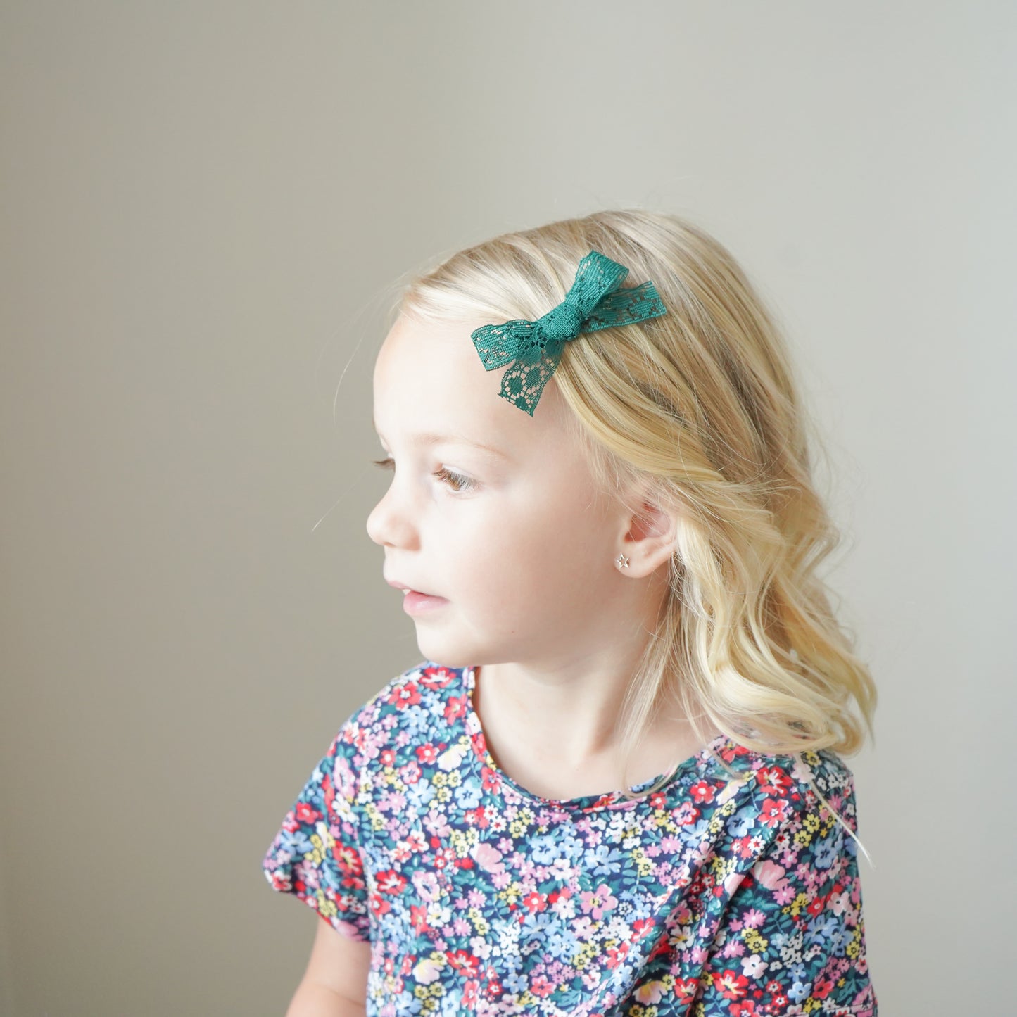 blonde girl with green bow in hair and floral dress village baby products gifts accessories