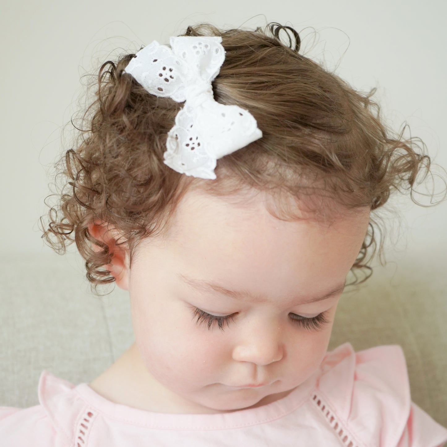 Little girl with white bow clip Village Baby Charlotte Lace