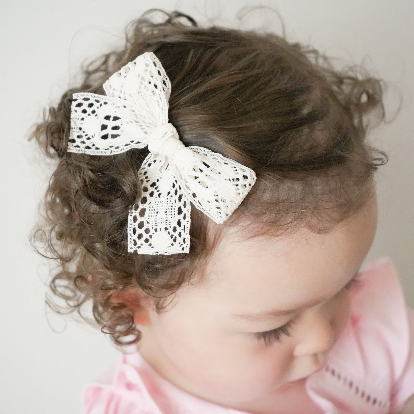 little girl wearing Abigal village baby lace bow in curly hair