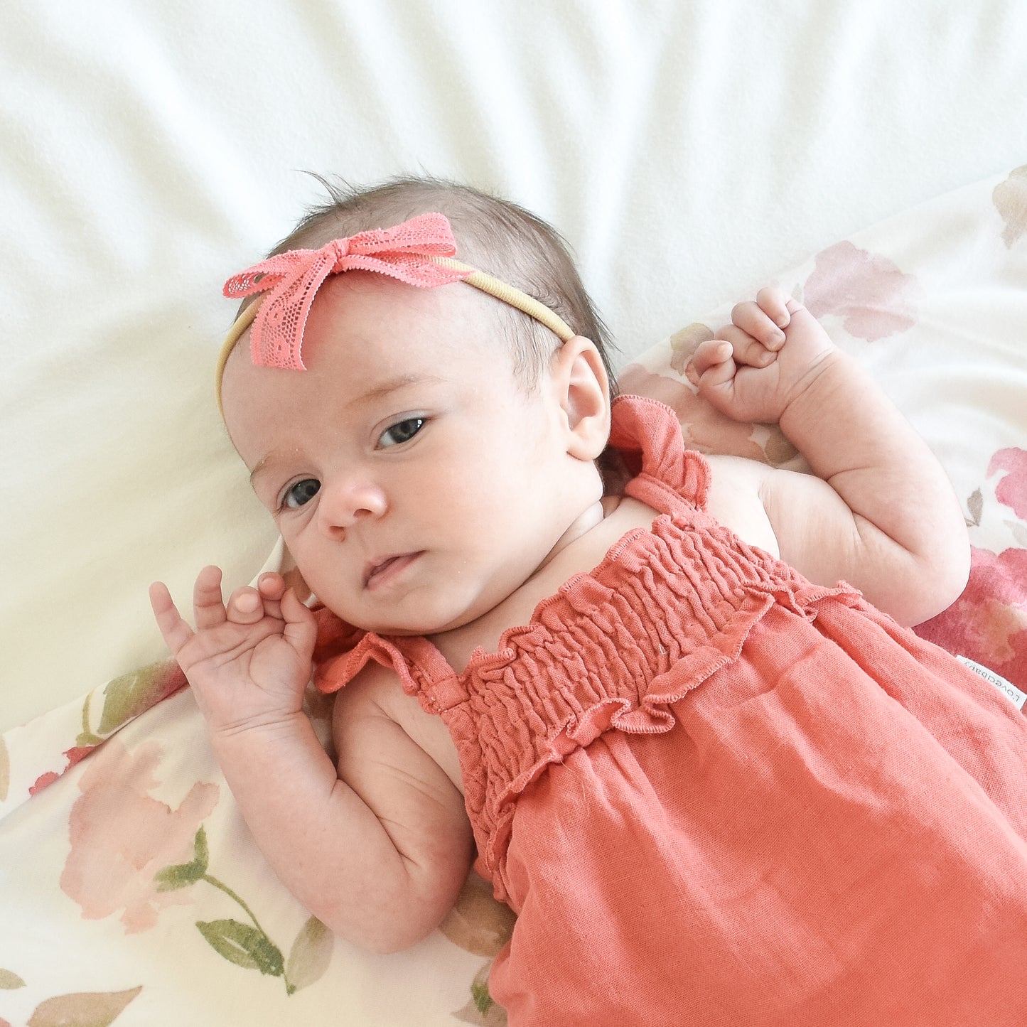 baby girl in dusty orange coral outfit with lace bow