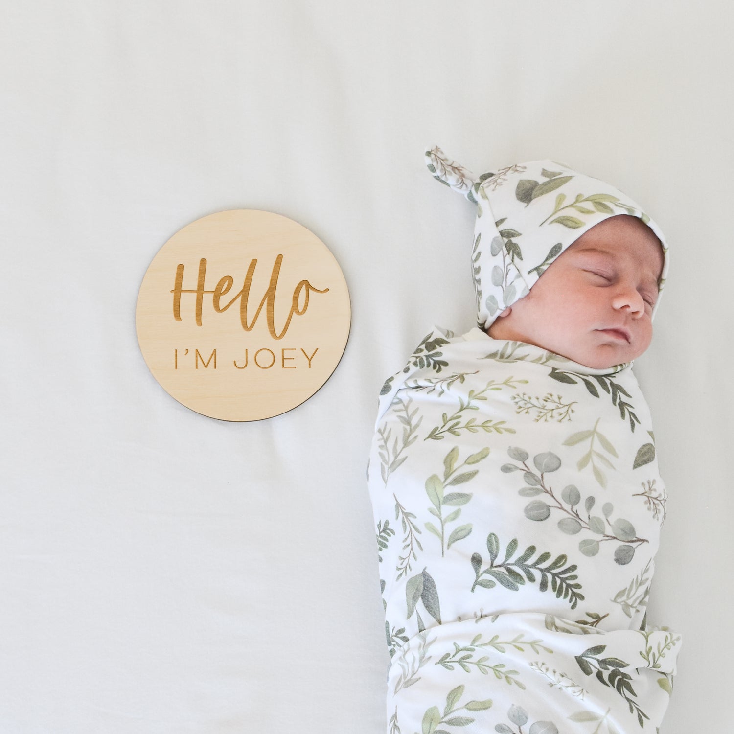 baby in graceful greenery blanket and hat set with custom name sign