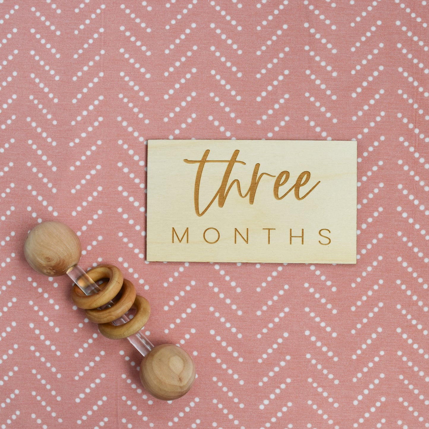 three months wood sign with baby rattle on desert dots swaddle by village baby