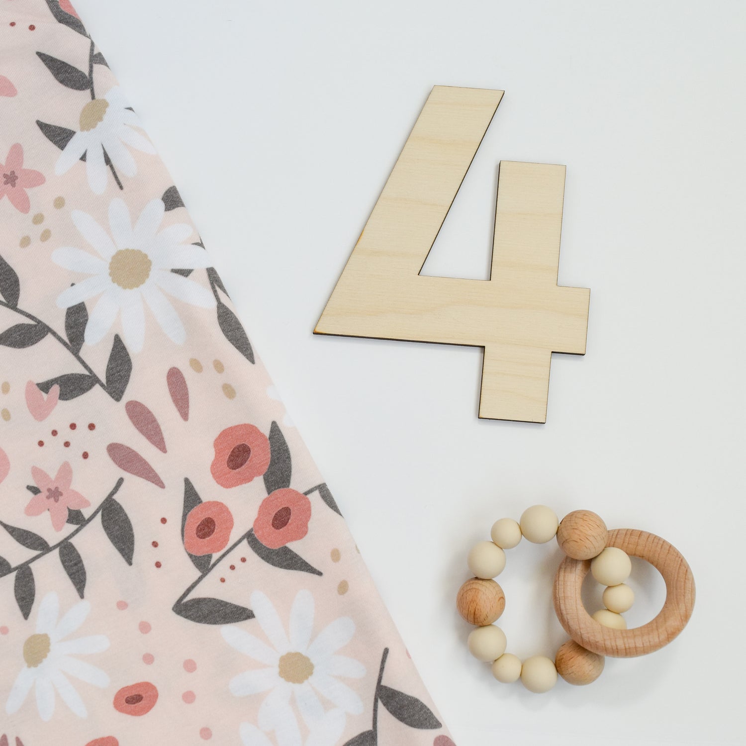 peach posey swaddle blanket with number four bold cutout milestone and rattle